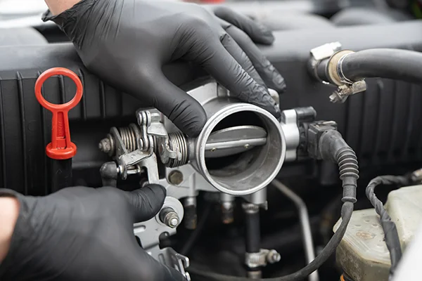 Gloved hands working on throttle body in engine bay