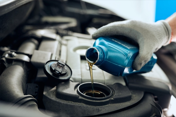 tech pouring oil into vehicle 